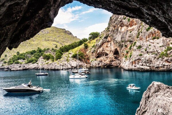 A breathtaking view of Mallorca coastline with clear blue waters, lush greenery, and a picturesque village.