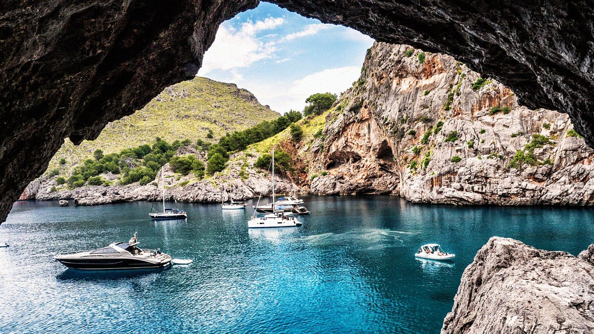 A breathtaking view of Mallorca coastline with clear blue waters, lush greenery, and a picturesque village.